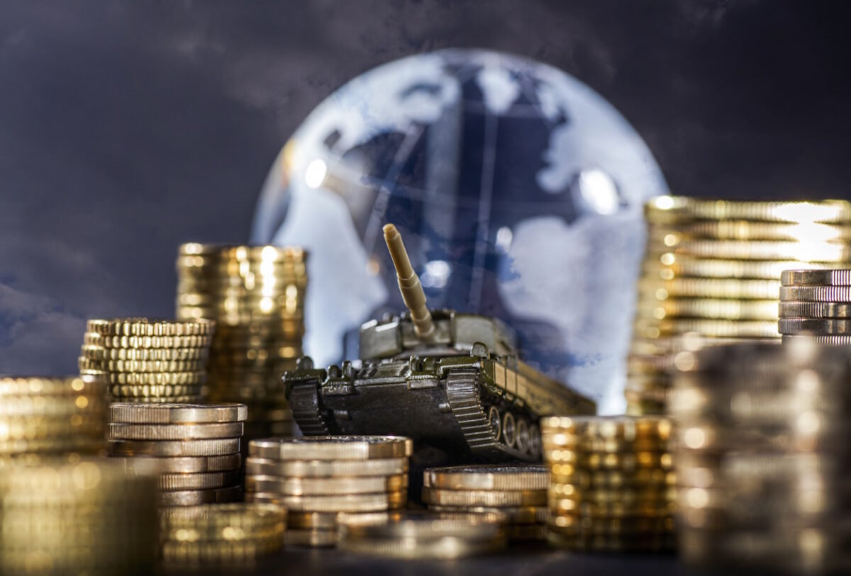 Stacks of money and a tank in front of a globe symbolizing global armament and finance