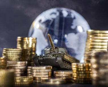 Stacks of money and a tank in front of a globe symbolizing global armament and finance