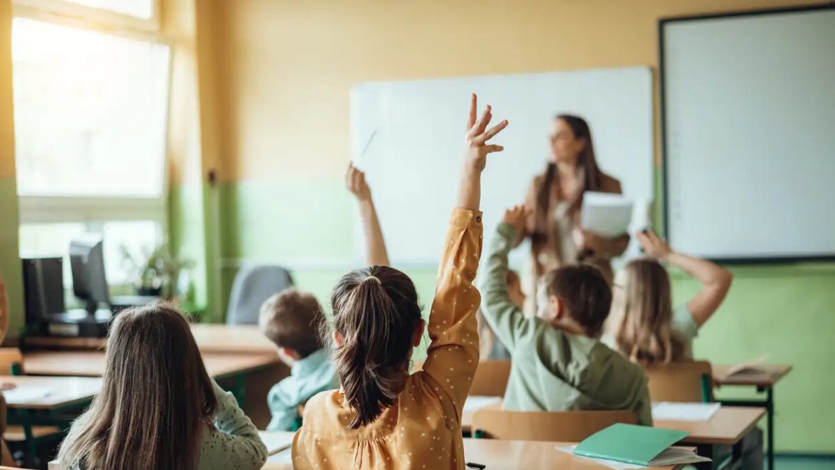 Students raising hands while teacher asking them questions in classroom