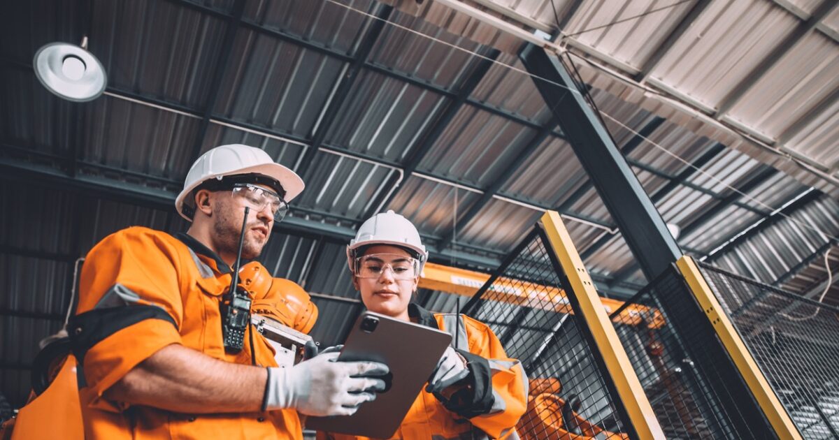 Engineer team service robot welding working in automation factory. People worker in safety suit work robotic arm software programming or replacing part in automated manufacturing industry technology.