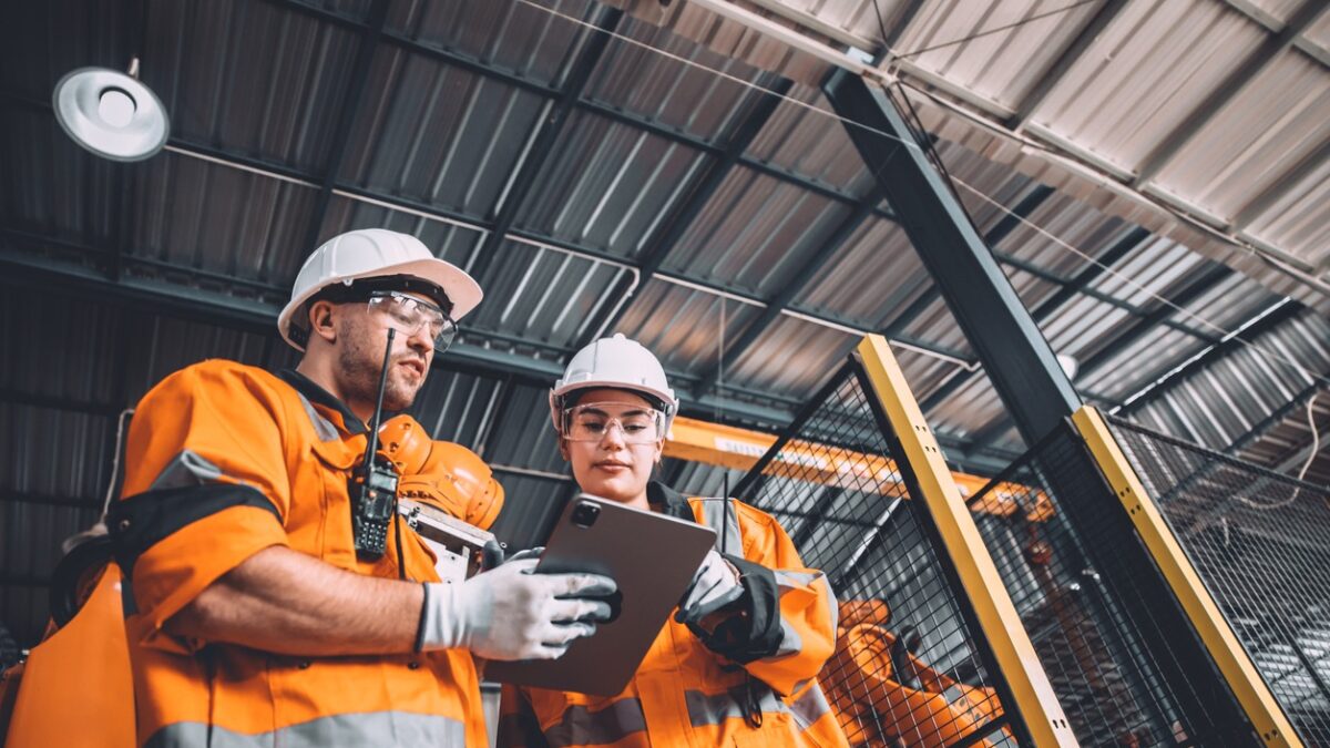 Engineer team service robot welding working in automation factory. People worker in safety suit work robotic arm software programming or replacing part in automated manufacturing industry technology.
