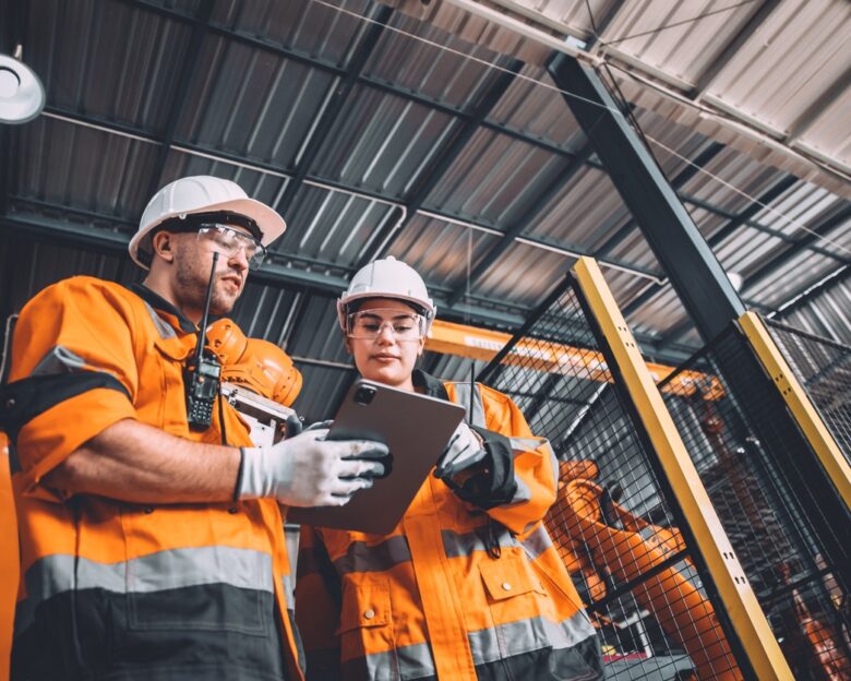 Engineer team service robot welding working in automation factory. People worker in safety suit work robotic arm software programming or replacing part in automated manufacturing industry technology.