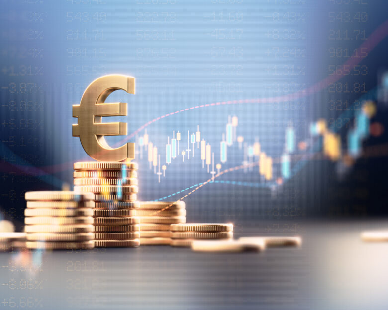 Euro symbol on top of coin stacks before blue financial graph. Horizontal composition with copy space. Business and finance concept.