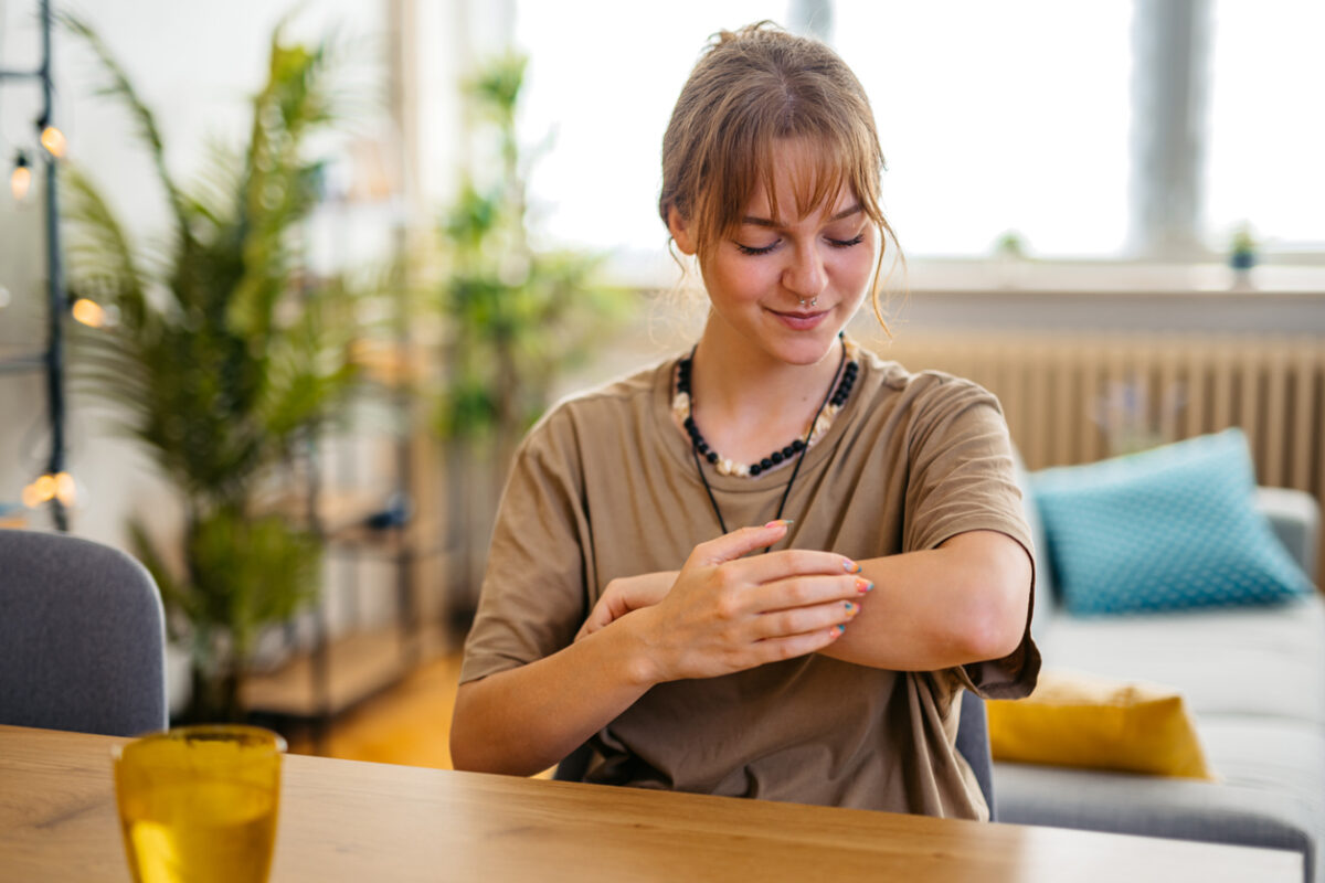 Young woman suffering from skin allergy, scratching her forearm