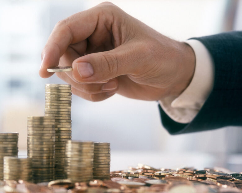 Hand of a mid adult man, wearing a siut, is stacking Euro coins. (2XL-File)