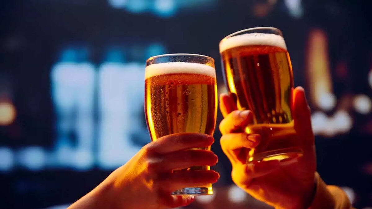 Hands holding lager light foamy big beer glasses and clinking. Two friends sitting in bar and drinking alcohol drinks. Concept of Beer Fest, party, celebration, taste, national traditions.