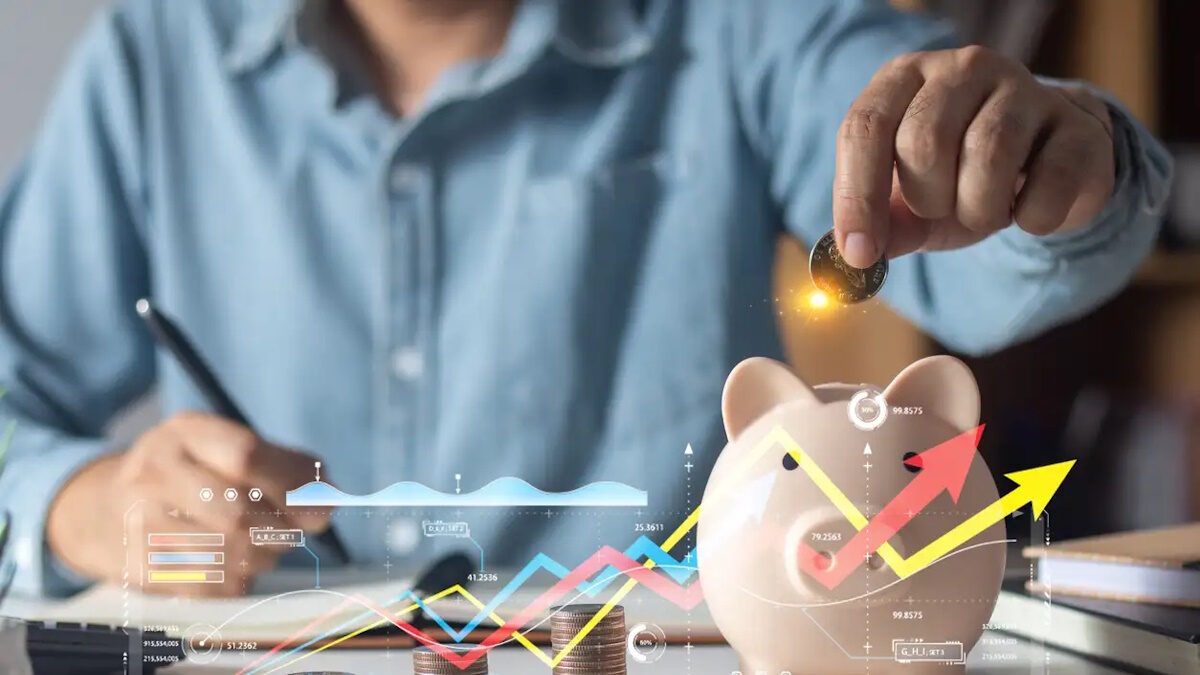 Man putting coins in piggy bank and taking notes in notebook money saving concept business