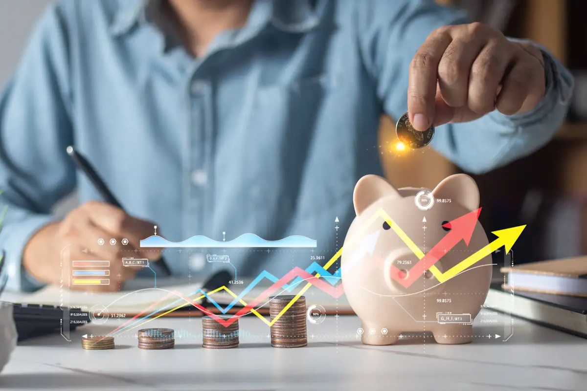 Man putting coins in piggy bank and taking notes in notebook money saving concept business