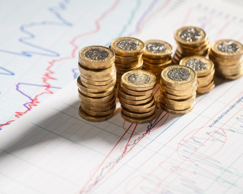Stack of pound coins on financial graphs and figures