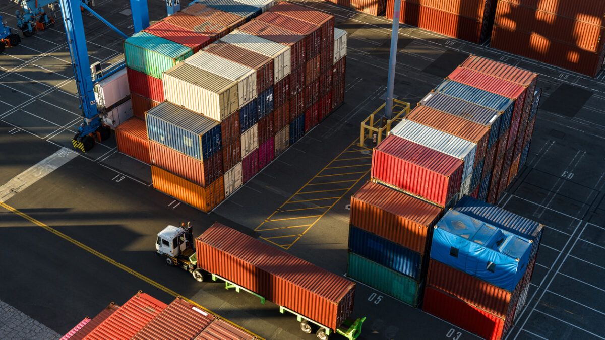 Drone shot of a terminal tractor driving between shipping containers in a massive intermodal container yard in the Port of Long Beach at sunset. Authorization was obtained from the Port of Long Beach Security Division and POLB Harbor Patrol for this operation in restricted airspace.