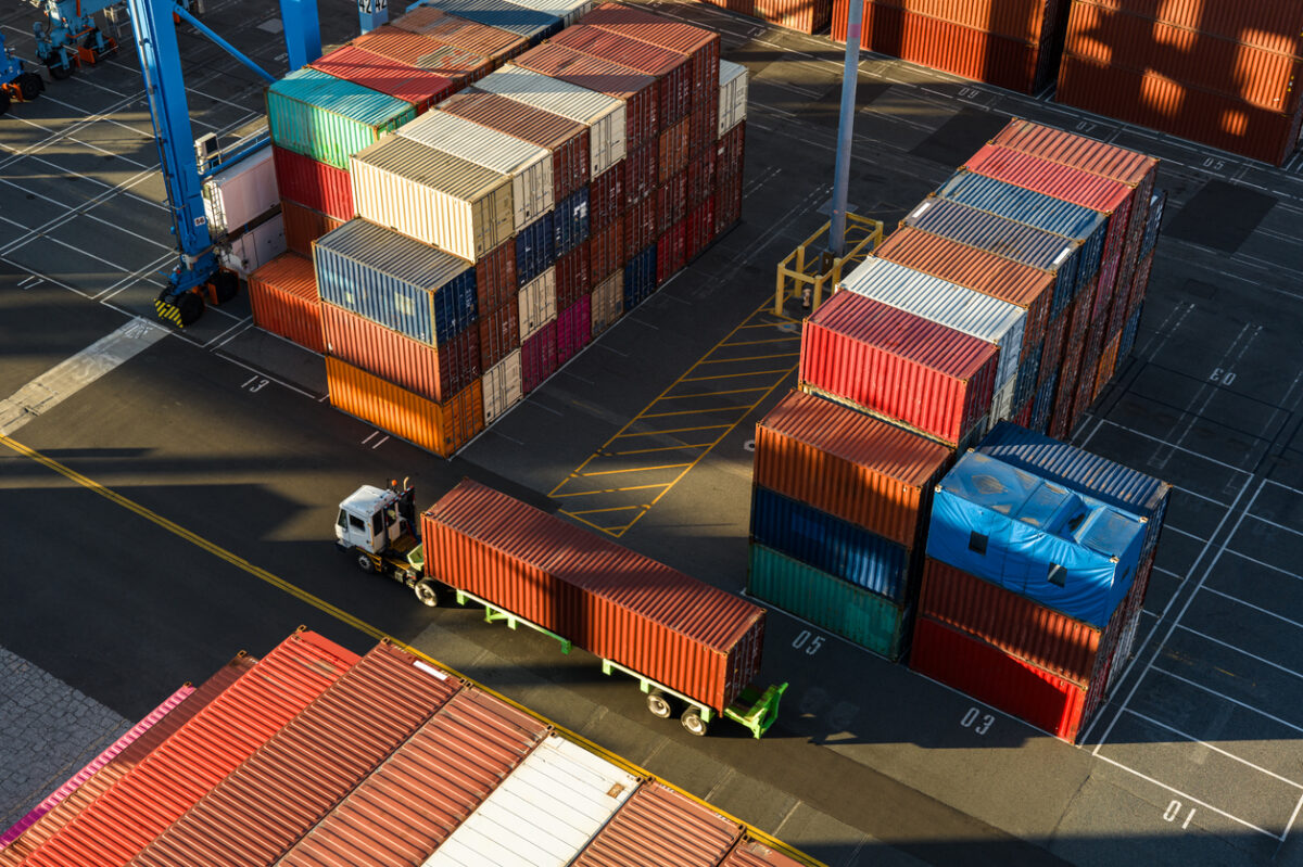 Drone shot of a terminal tractor driving between shipping containers in a massive intermodal container yard in the Port of Long Beach at sunset. Authorization was obtained from the Port of Long Beach Security Division and POLB Harbor Patrol for this operation in restricted airspace.