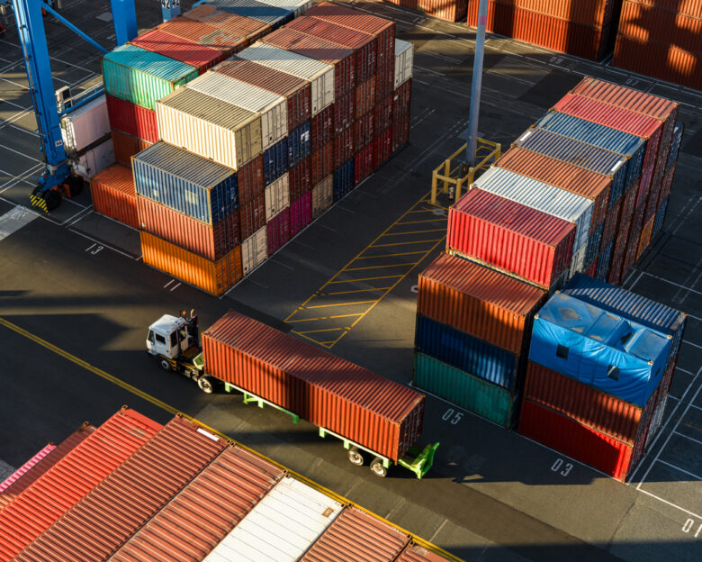 Drone shot of a terminal tractor driving between shipping containers in a massive intermodal container yard in the Port of Long Beach at sunset. Authorization was obtained from the Port of Long Beach Security Division and POLB Harbor Patrol for this operation in restricted airspace.