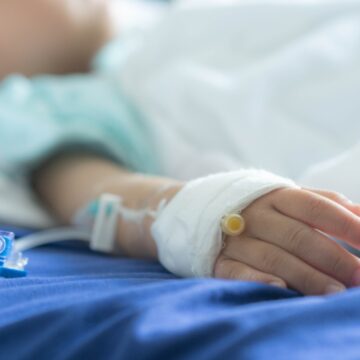 an Asian todler in hospital with intravenous saline. Sick children, infected with the virus, are lying and being treated in beds in hospitals.