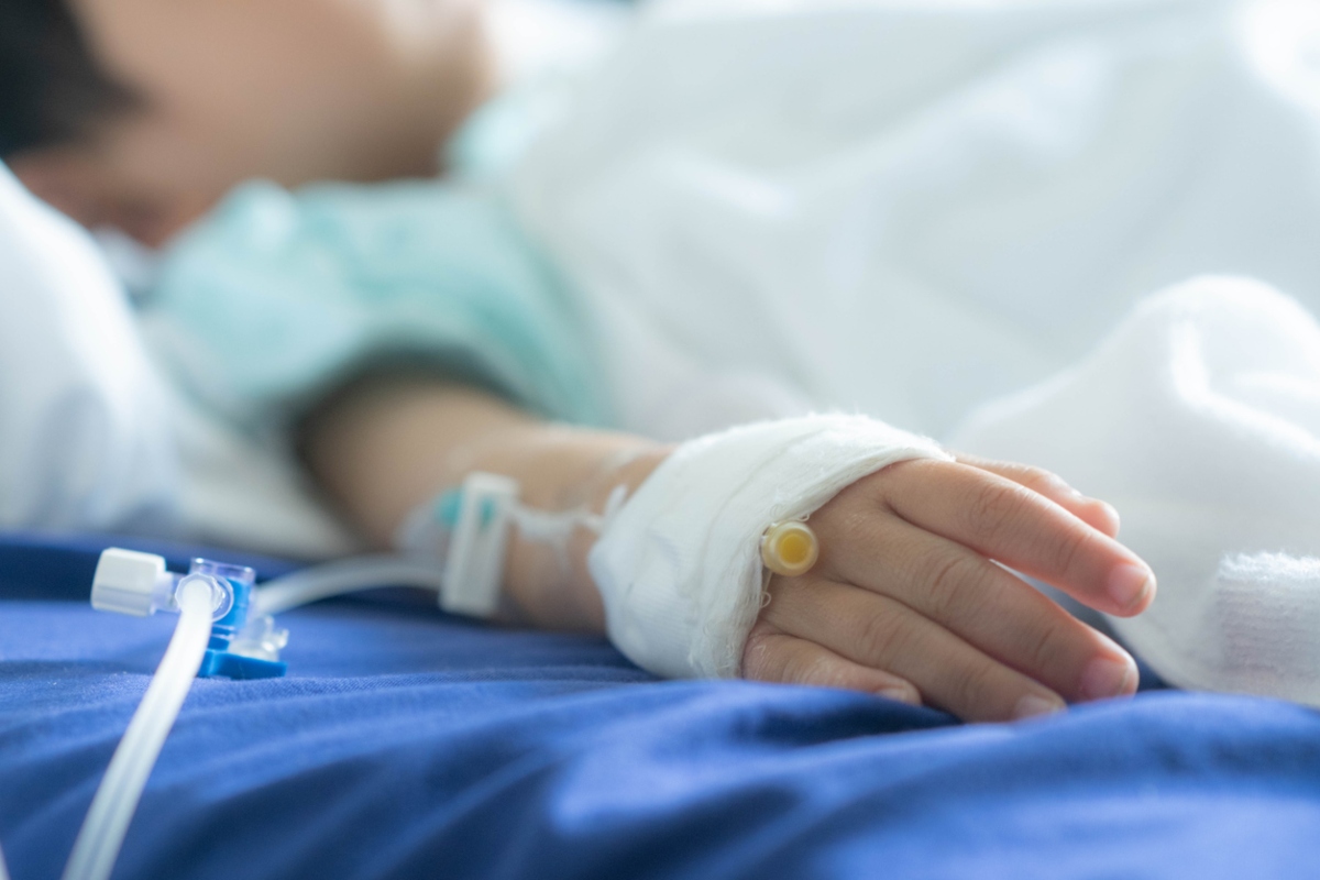 an Asian todler in hospital with intravenous saline. Sick children, infected with the virus, are lying and being treated in beds in hospitals.