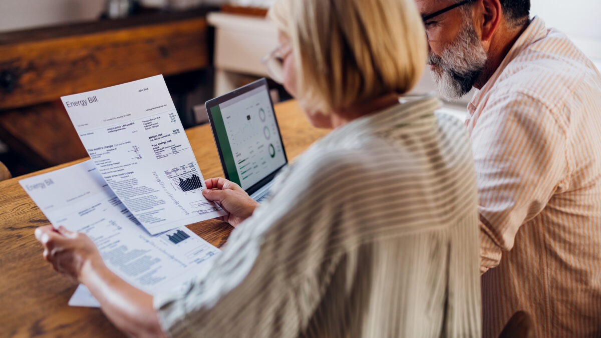 Senior couple carefully reviewing their household energy bill together on a laptop at home. They seem focused and concerned