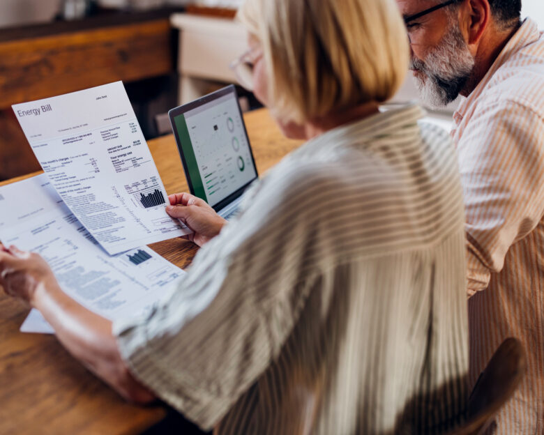 Senior couple carefully reviewing their household energy bill together on a laptop at home. They seem focused and concerned