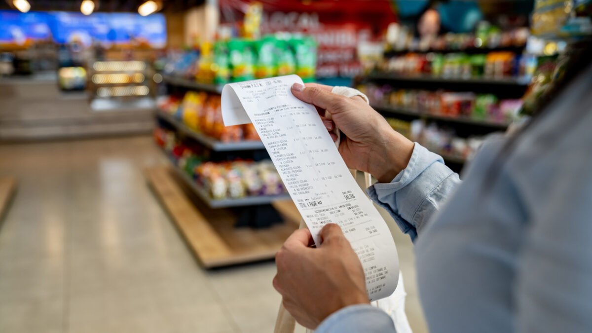 Close-up on a woman shopping at a convenience store and checking her receipt while exiting