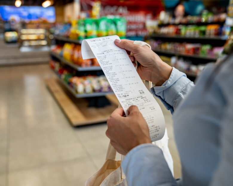 Close-up on a woman shopping at a convenience store and checking her receipt while exiting