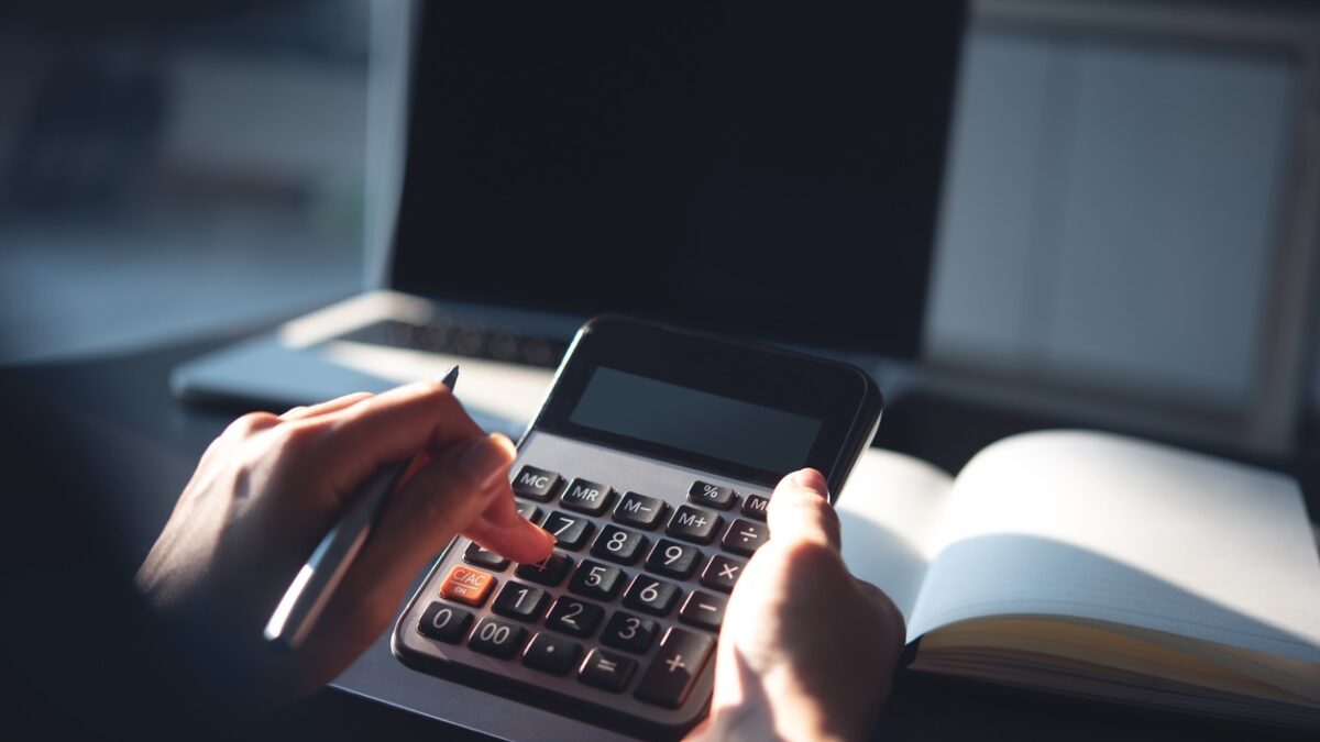 Close up, business woman working at office, using calculator to calculate company finance, accounting with laptop computer on table, budget management. Doing home finance, budgeting and tax calculation
