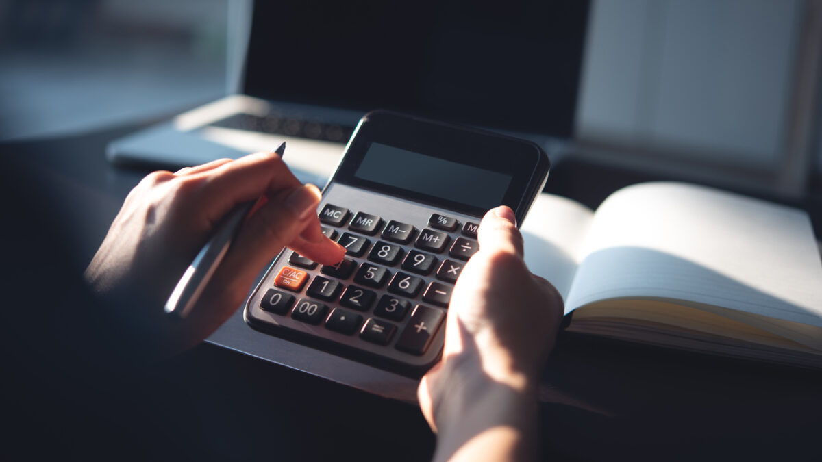 Close up, business woman working at office, using calculator to calculate company finance, accounting with laptop computer on table, budget management. Doing home finance, budgeting and tax calculation