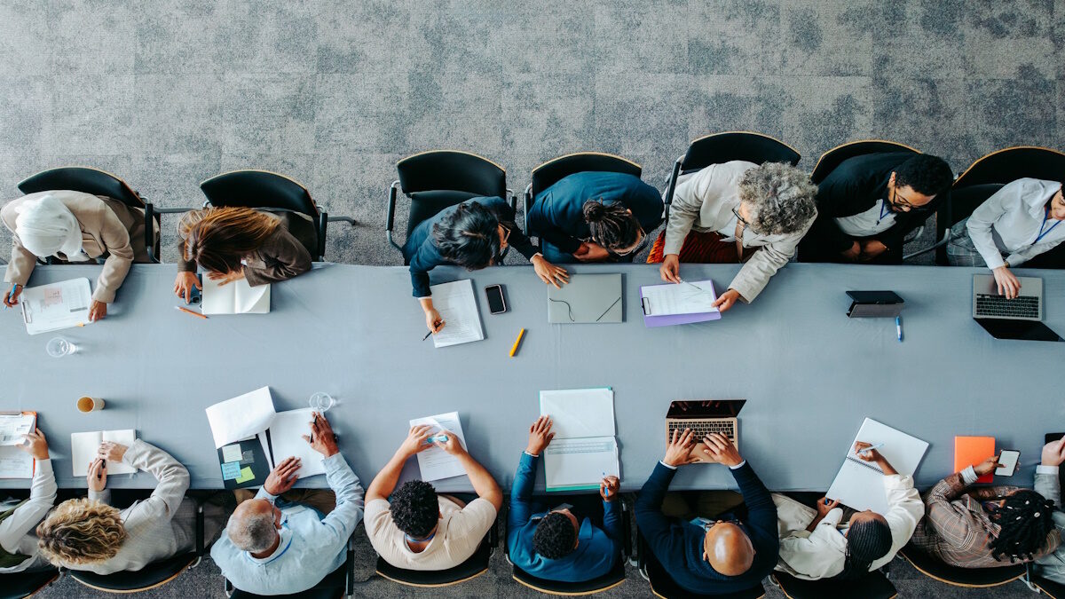 Top view of diverse business group in office meeting, collaborating and discussing around a large table.