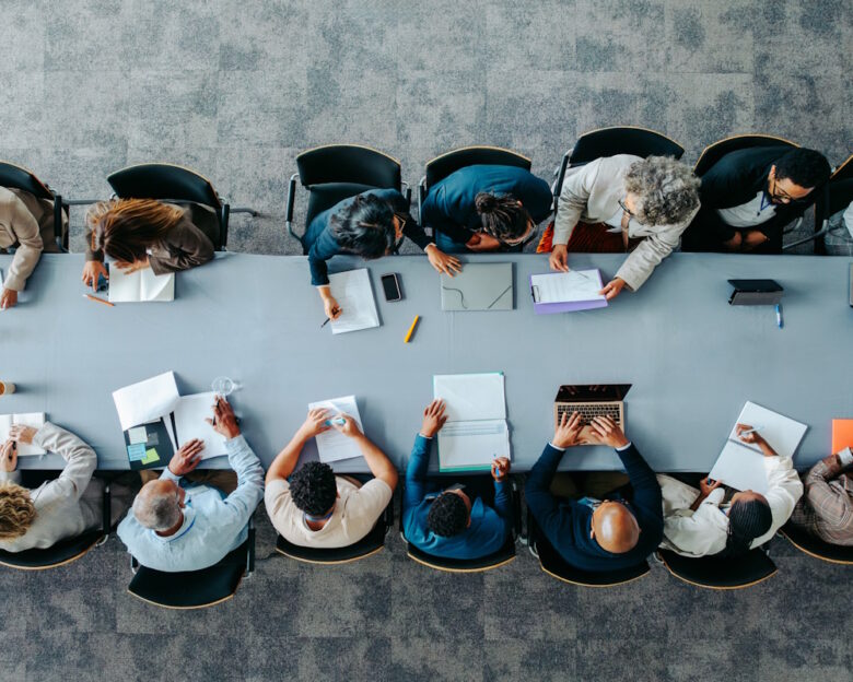 Top view of diverse business group in office meeting, collaborating and discussing around a large table.