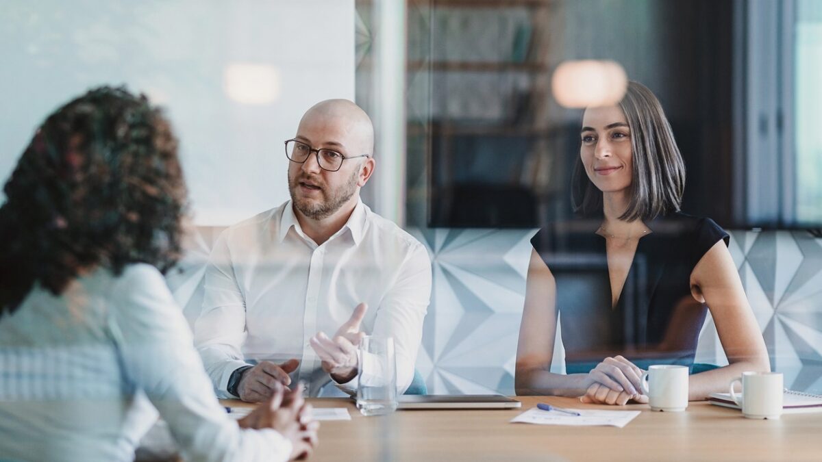 Group of business persons having a meeting behind a glass wall