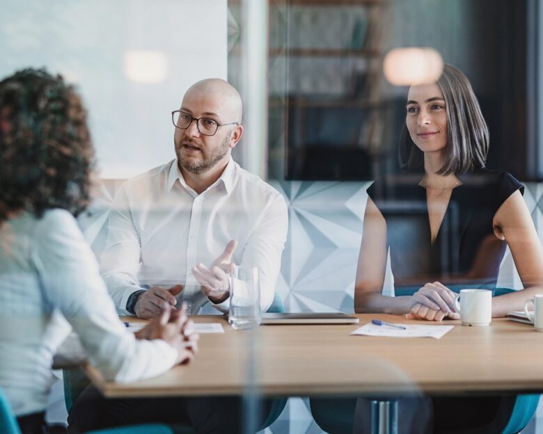 Group of business persons having a meeting behind a glass wall