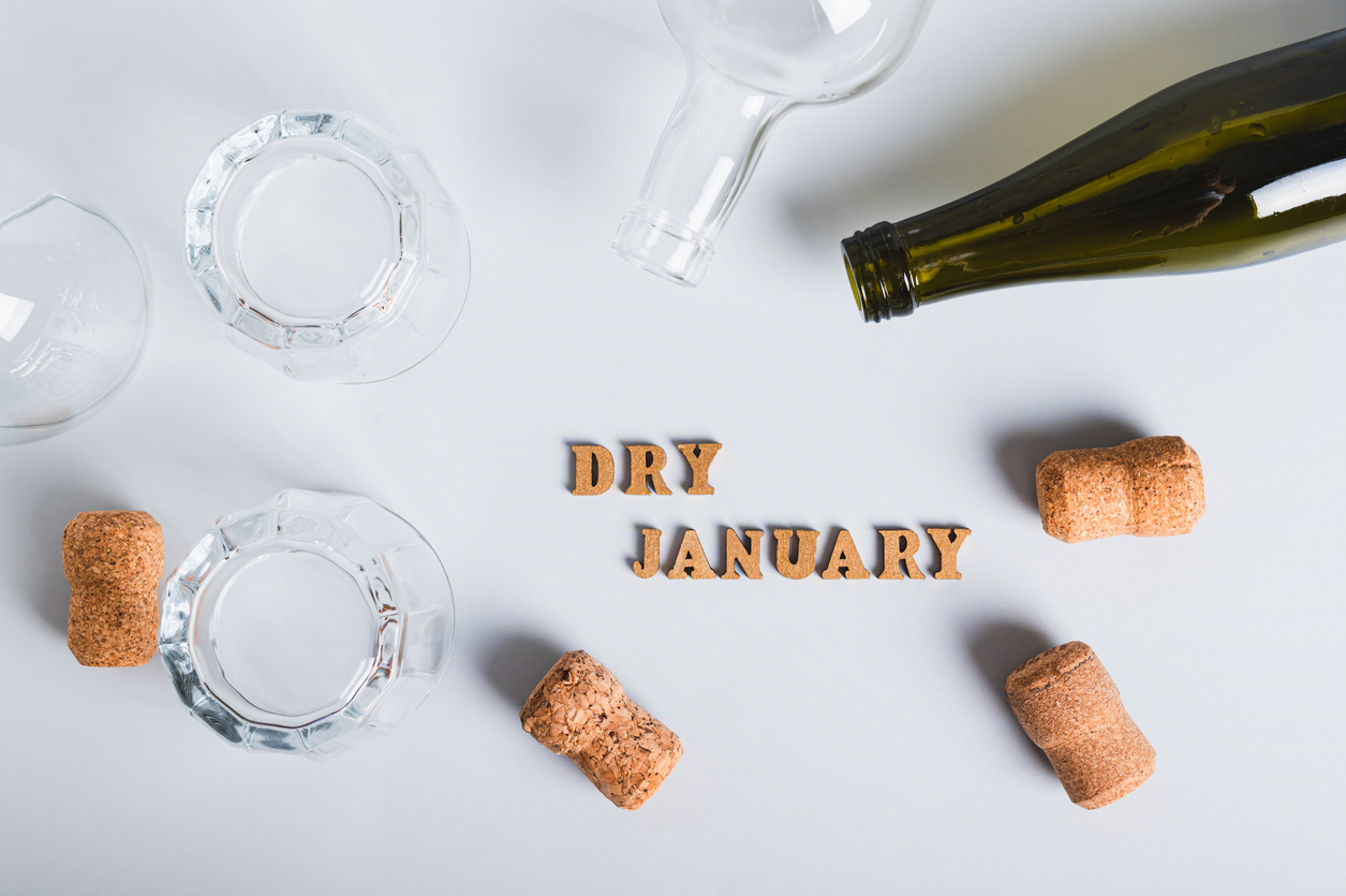 Dry January concept, empty glasses, bottles and corks on a gray background top view