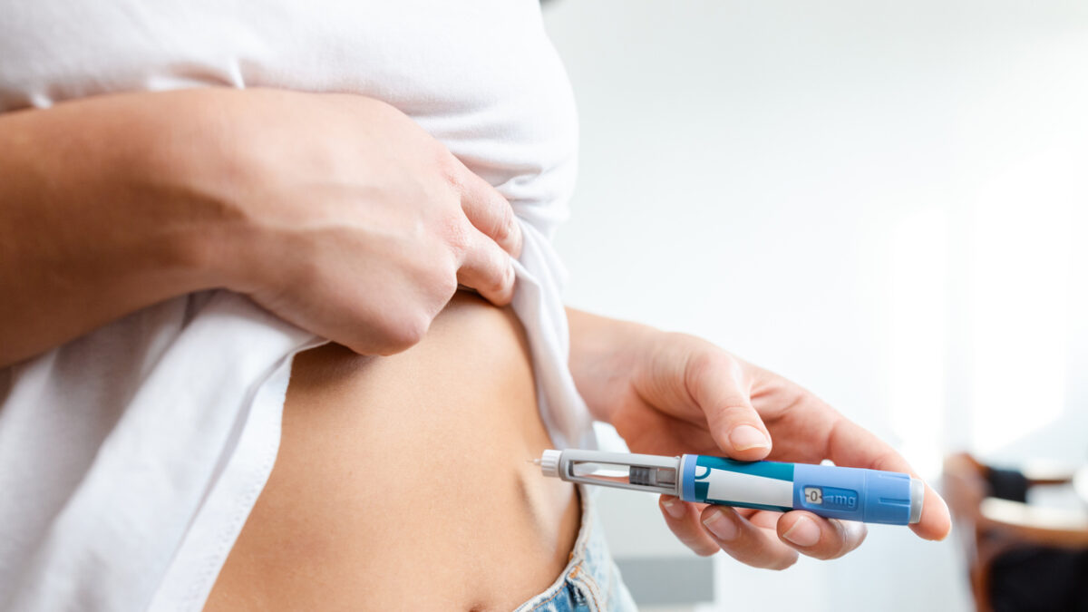 Image of an individual injecting insulin into their abdomen using a pen device. Demonstrates healthcare, diabetes management, and medication administration domestically, conveying a sense of responsibility and self-care.
