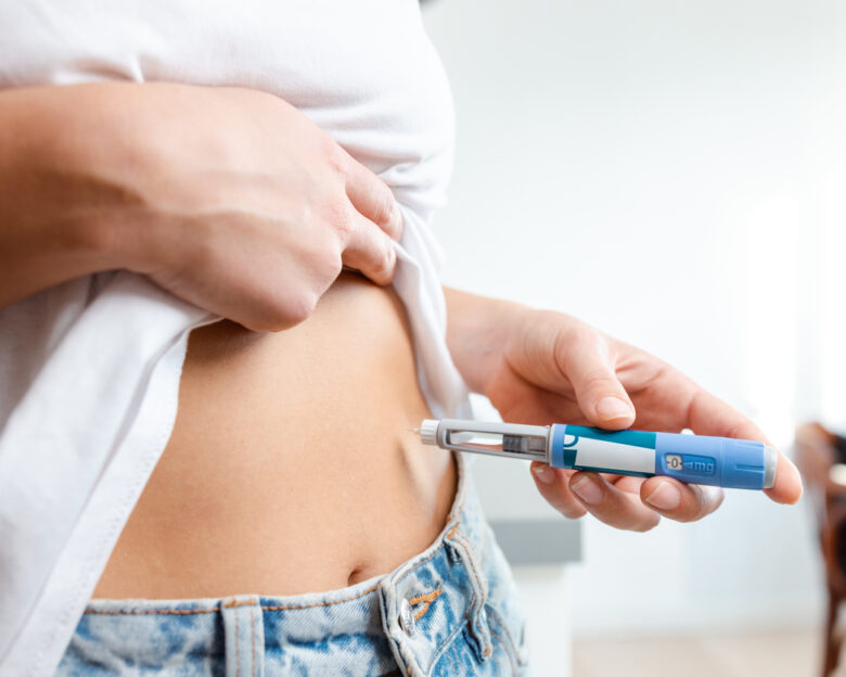 Image of an individual injecting insulin into their abdomen using a pen device. Demonstrates healthcare, diabetes management, and medication administration domestically, conveying a sense of responsibility and self-care.