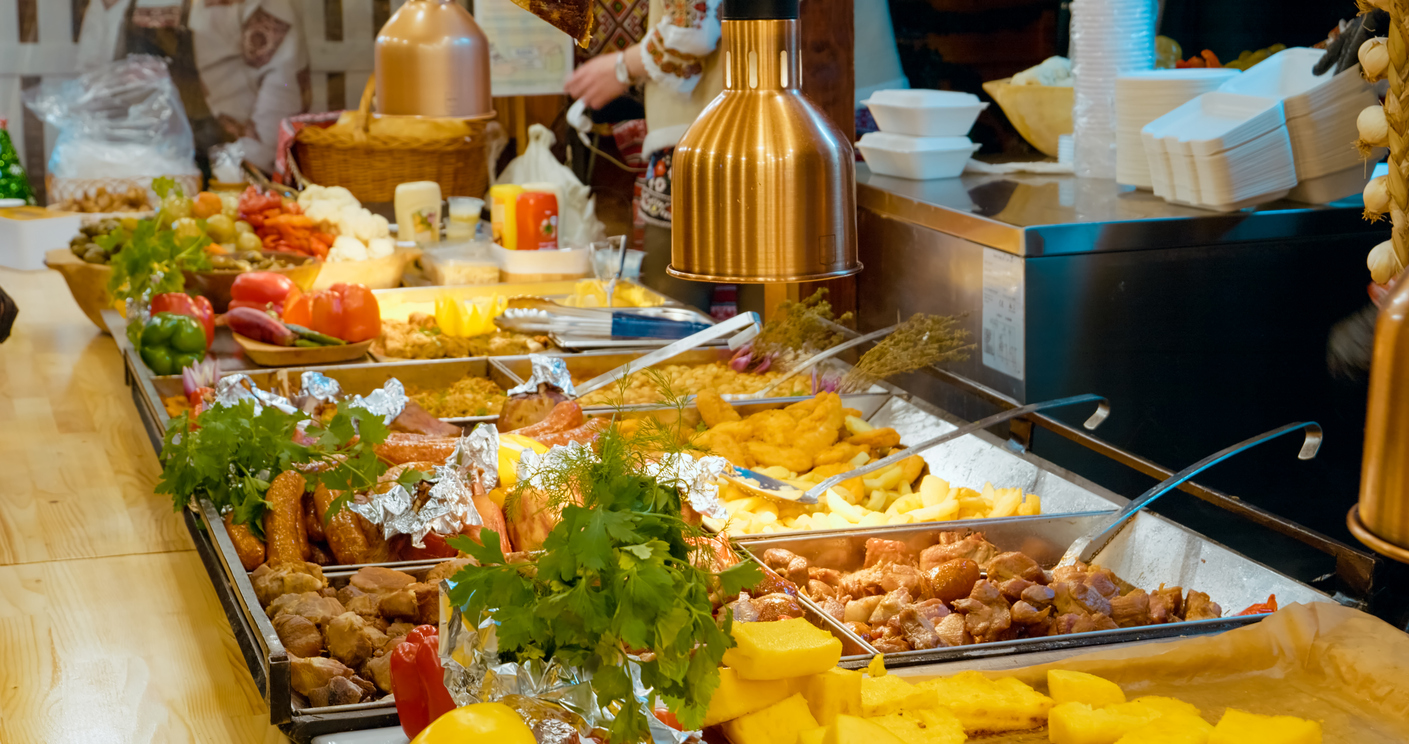 Traditional Romanian street food served by a chef wearing a Romanian folk costume at a Christmas market