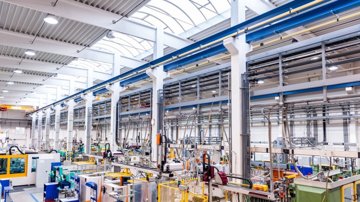 Color image of futuristic new factory producing plastic pieces for car industry. Factory modern interior where is placed a lot of robot machines which provide work for human, space for copy. Modern indoor hall for assembly. Large group of automated injection moulding machines for plastic parts production.