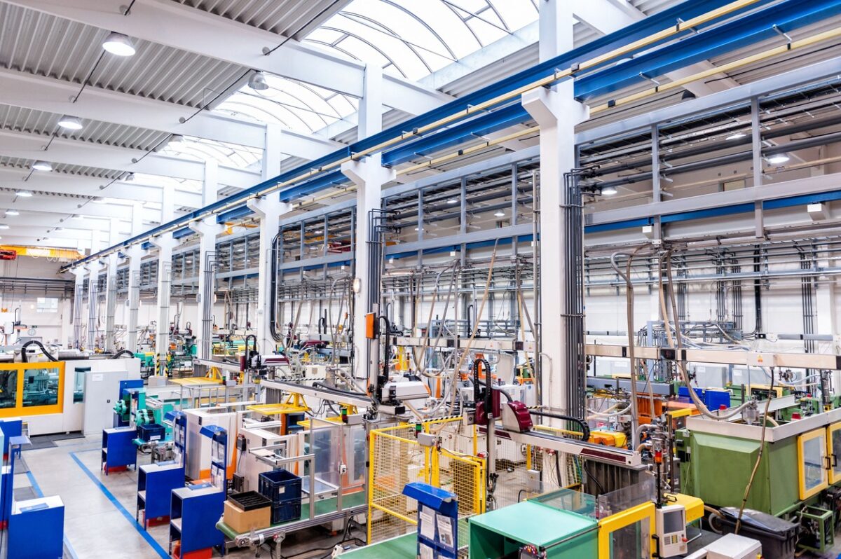 Color image of futuristic new factory producing plastic pieces for car industry. Factory modern interior where is placed a lot of robot machines which provide work for human, space for copy. Modern indoor hall for assembly. Large group of automated injection moulding machines for plastic parts production.