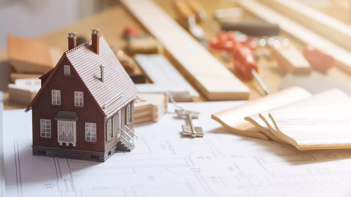 Construction and home renovation concept, model house, work tools, house keys and draft project on a desktop