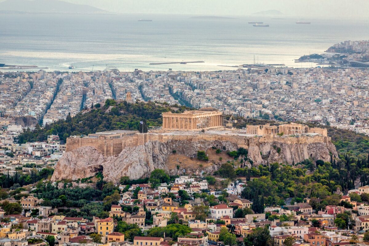 Aerial view over the city of Athens towards the mediterranean sea with the famous ancient greek Athens Acropolis in the center. Athens, Greece.