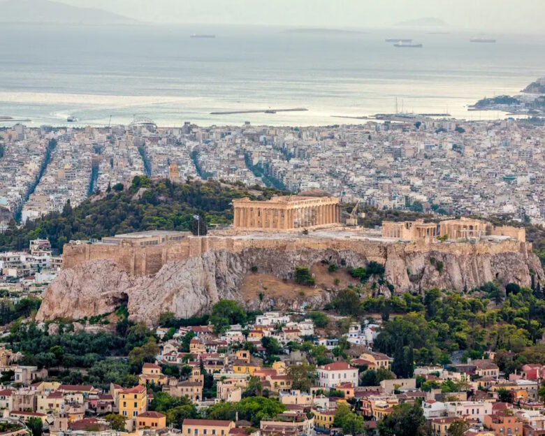 Aerial view over the city of Athens towards the mediterranean sea with the famous ancient greek Athens Acropolis in the center. Athens, Greece.