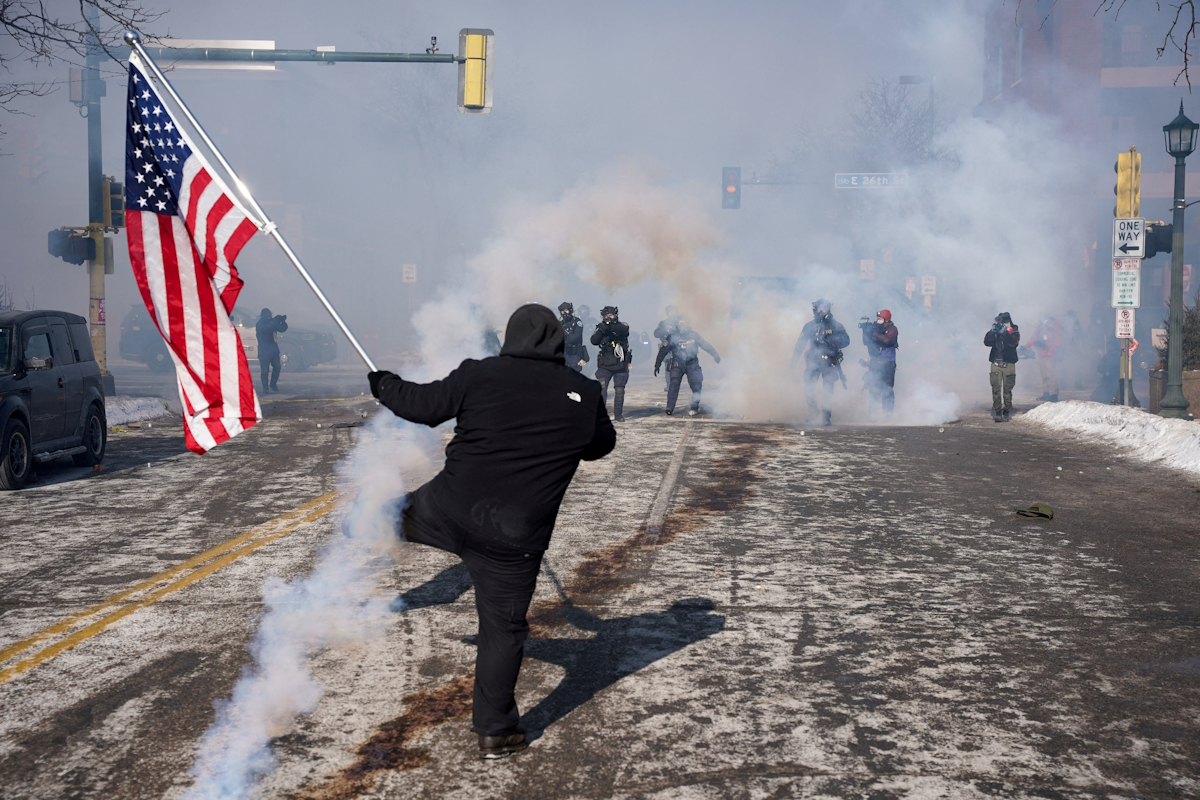 Ένα άτομο κρατά μια αμερικανική σημαία κατά τη διάρκεια συγκρούσεων μεταξύ ομοσπονδιακών πρακτόρων και μελών της κοινότητας στο σημείο όπου ομοσπονδιακοί πράκτορες πυροβόλησαν θανάσιμα έναν άνδρα ενώ προσπαθούσαν να τον συλλάβουν, στη Μινεάπολη της Μινεσότα