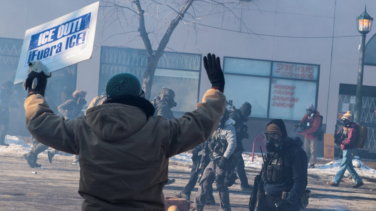 Άνδρας κρατάει πλακάτ καθώς ομοσπονδιακοί πράκτορες χρησιμοποιούν δακρυγόνα για να διαλύσουν τους ανθρώπους που συγκεντρώθηκαν κοντά στο σημείο όπου ομοσπονδιακοί πράκτορες πυροβόλησαν θανάσιμα έναν άνδρα ενώ προσπαθούσαν να τον συλλάβουν, στη Μινεάπολη της Μινεσότα, στις ΗΠΑ