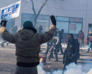 Άνδρας κρατάει πλακάτ καθώς ομοσπονδιακοί πράκτορες χρησιμοποιούν δακρυγόνα για να διαλύσουν τους ανθρώπους που συγκεντρώθηκαν κοντά στο σημείο όπου ομοσπονδιακοί πράκτορες πυροβόλησαν θανάσιμα έναν άνδρα ενώ προσπαθούσαν να τον συλλάβουν, στη Μινεάπολη της Μινεσότα, στις ΗΠΑ