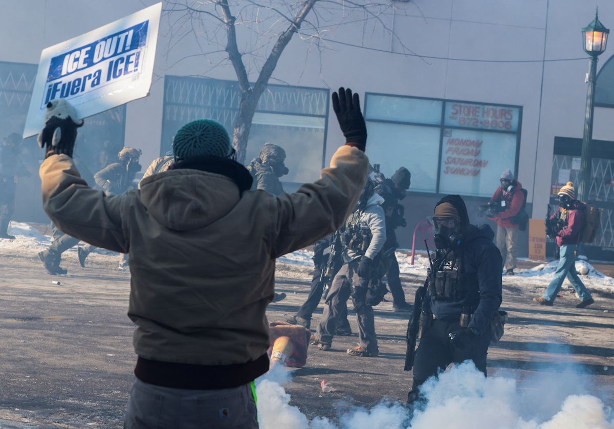 Άνδρας κρατάει πλακάτ καθώς ομοσπονδιακοί πράκτορες χρησιμοποιούν δακρυγόνα για να διαλύσουν τους ανθρώπους που συγκεντρώθηκαν κοντά στο σημείο όπου ομοσπονδιακοί πράκτορες πυροβόλησαν θανάσιμα έναν άνδρα ενώ προσπαθούσαν να τον συλλάβουν, στη Μινεάπολη της Μινεσότα, στις ΗΠΑ