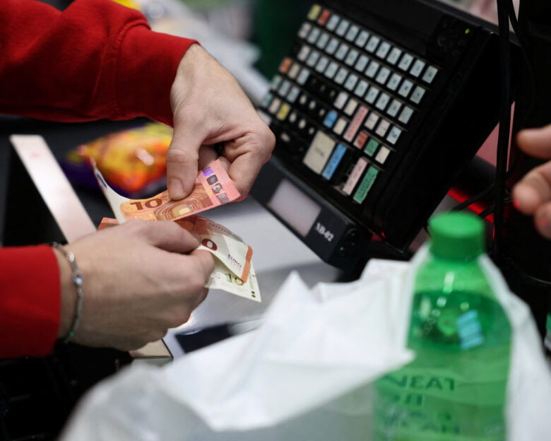 A person holds change in euros as customers shop in Fantastico store, on the day of the country’s accession to the Eurozone, in Sofia