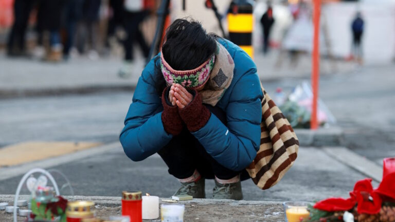 Άνθρωποι αποτίουν φόρο τιμής δίπλα στα κεριά που έχουν τοποθετηθεί για τα θύματα έξω από το μπαρ «Le Constellation», μετά από πυρκαγιά και έκρηξη κατά τη διάρκεια πάρτι της Πρωτοχρονιάς, όπου αρκετοί άνθρωποι έχασαν τη ζωή τους και άλλοι τραυματίστηκαν, σύμφωνα με την ελβετική αστυνομία, στο πολυτελές χιονοδρομικό κέντρο Crans-Montana στη νοτιοδυτική Ελβετία