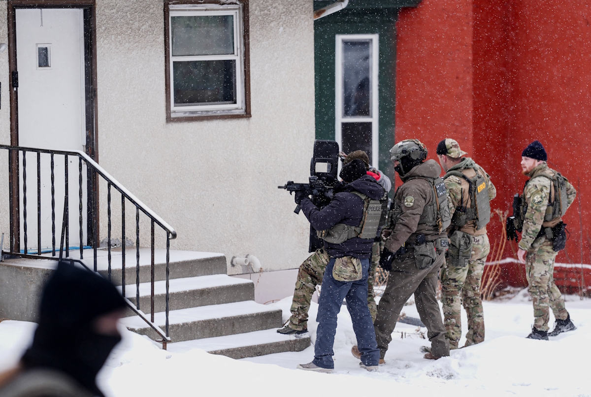 Ένας αστυνομικός σημαδεύει με όπλο ένα σπίτι κατά τη διάρκεια επιδρομής της υπηρεσίας μετανάστευσης στο Σεντ Πολ της Μινεσότα