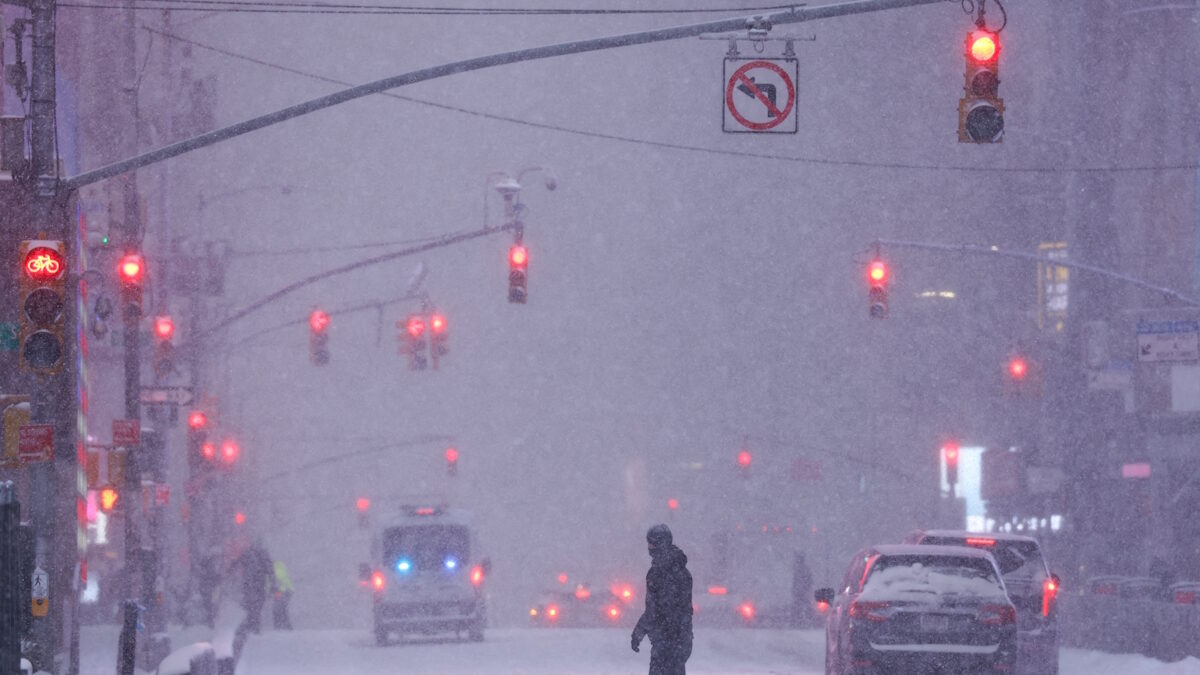 Ένας άνθρωπο διασχίζει το δρόμο κατά τη διάρκεια χιονόπτωσης κοντά στην Times Square, καθώς μια μεγάλη χειμερινή καταιγίδα εξαπλώνεται σε μια μεγάλη περιοχή των Ηνωμένων Πολιτειών