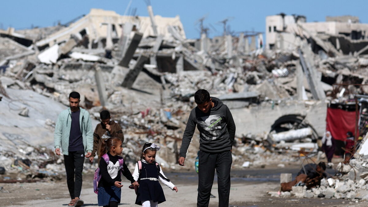 Παλαιστίνιοι περπατούν ανάμεσα στα ερείπια κατοικιών που καταστράφηκαν κατά τη διάρκεια της διετούς ισραηλινής επίθεσης, στην πόλη της Γάζας