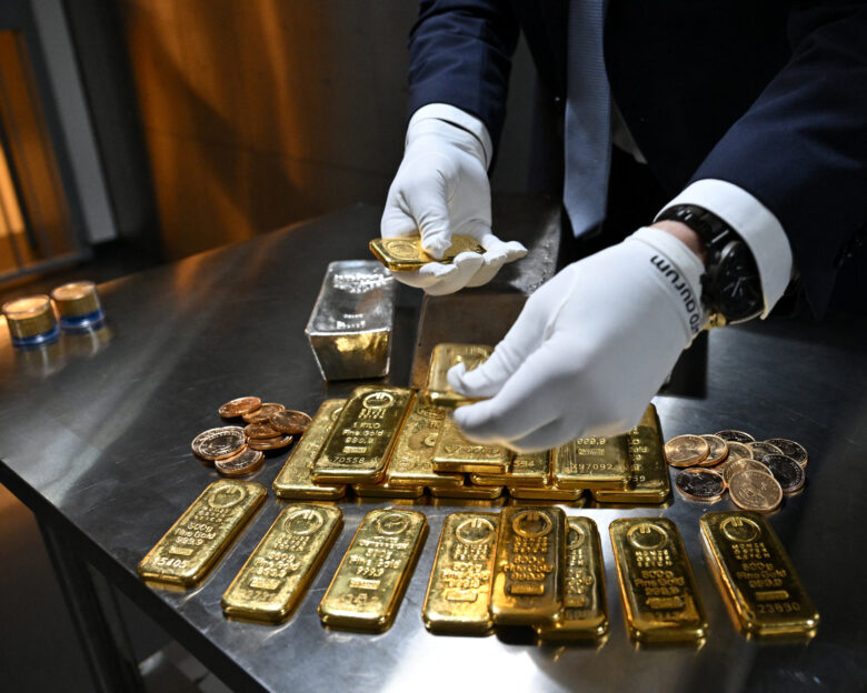 Υπάλληλος κρατά ράβδους χρυσού σε θησαυροφυλάκιο