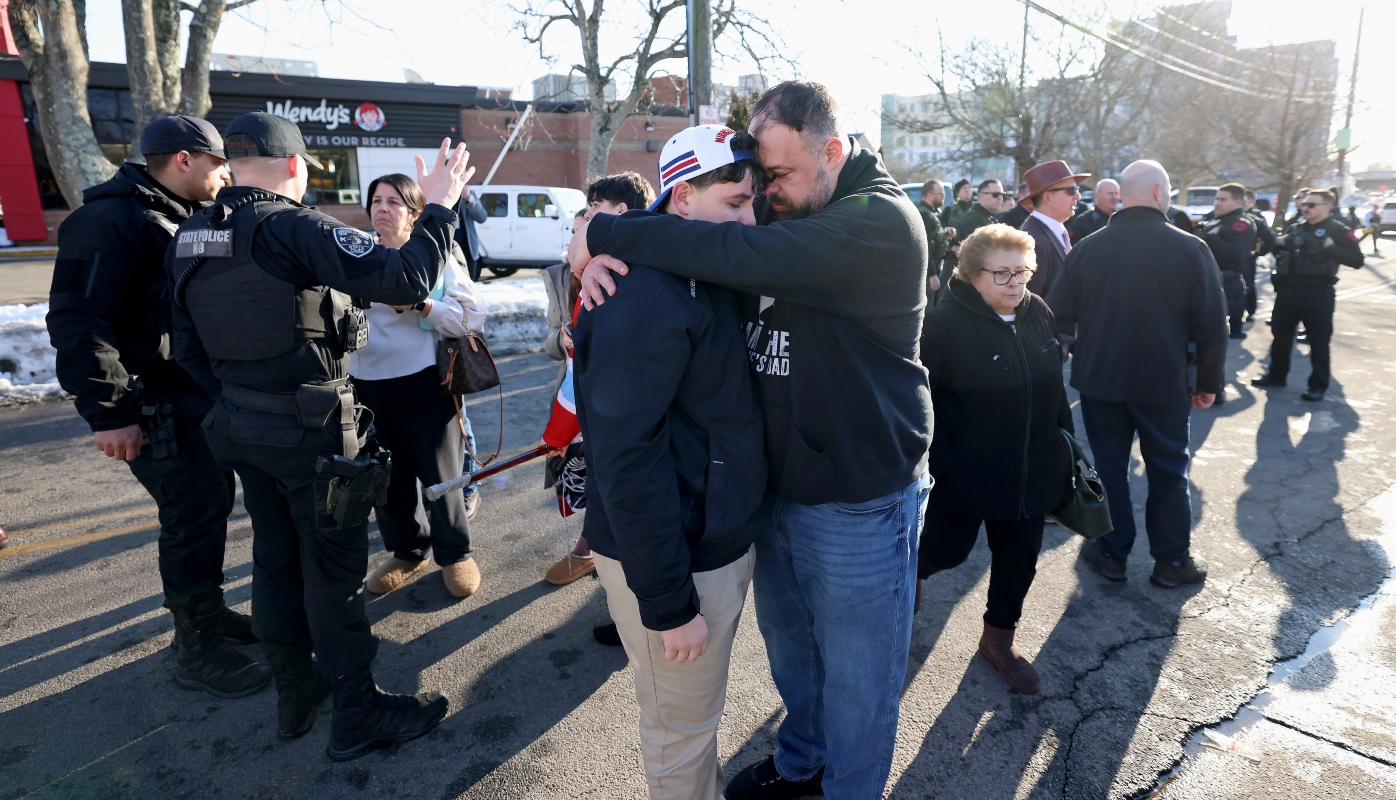 A father hugs his son outside of the Lynch Arena in Pawtucket, R.I., after a shooting at the ice rink, Monday, Feb. 16, 2026.