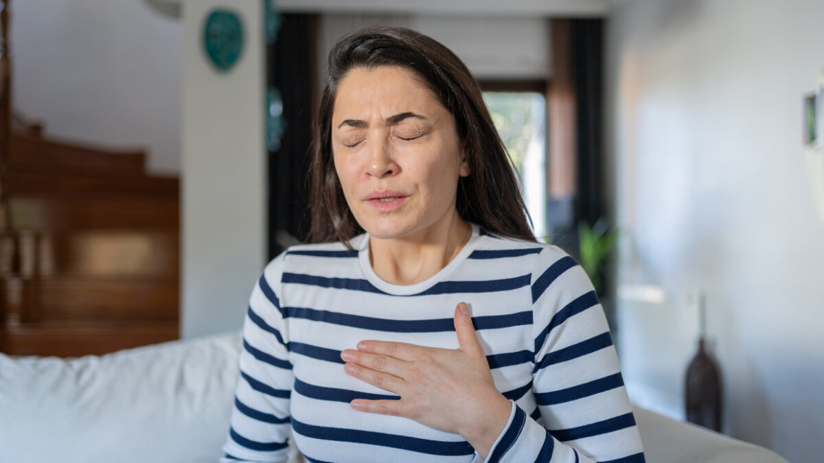 Woman With A Panic Attack Having Trouble Breathing Sitting On Sofa At Home