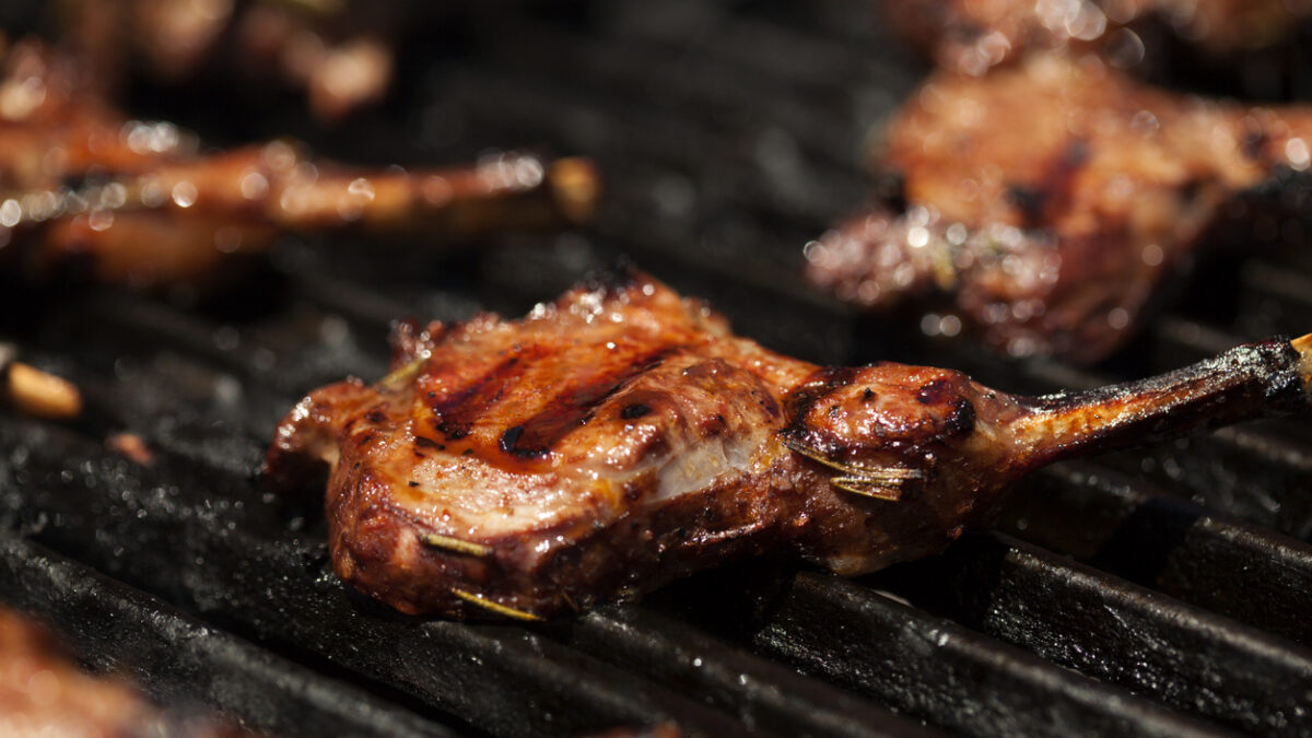 Closeup of grilling juicy lamb chops on grill grates. Narrow DOF.